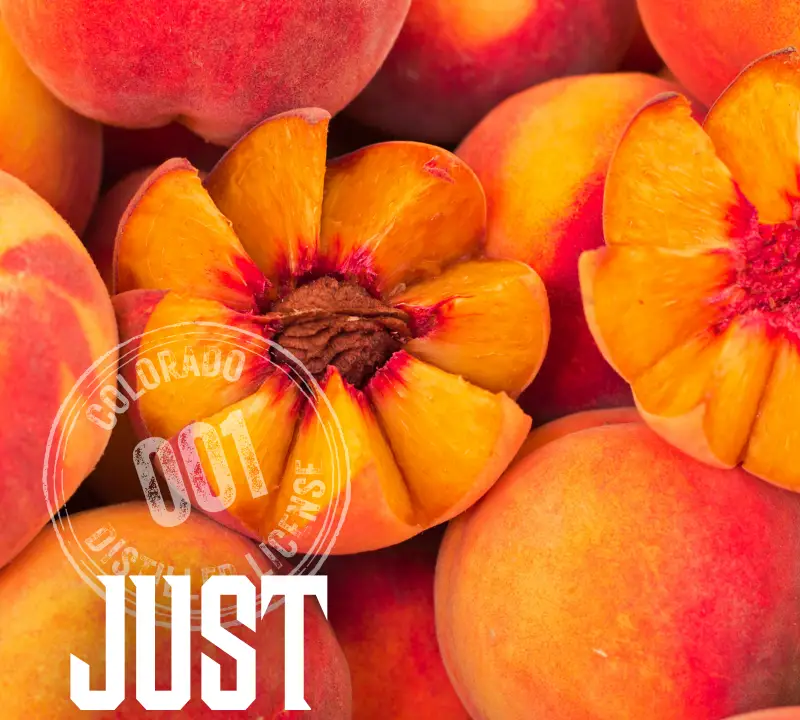 A close-up of ripe peaches, with one peach cut open to reveal its stone. Overlaid text reads JUST PEACHY with Peach Street Distillers and a Colorado distilling license stamp in the corner, celebrating the natural bounty of Colorado—perfect for an Earth Day toast.